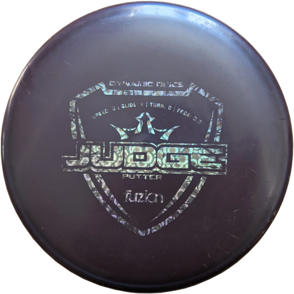 Used 7/10 Judge in Fuzion plastic from Dynamic Discs. The colour is Dark Purple with a Silver stamp.